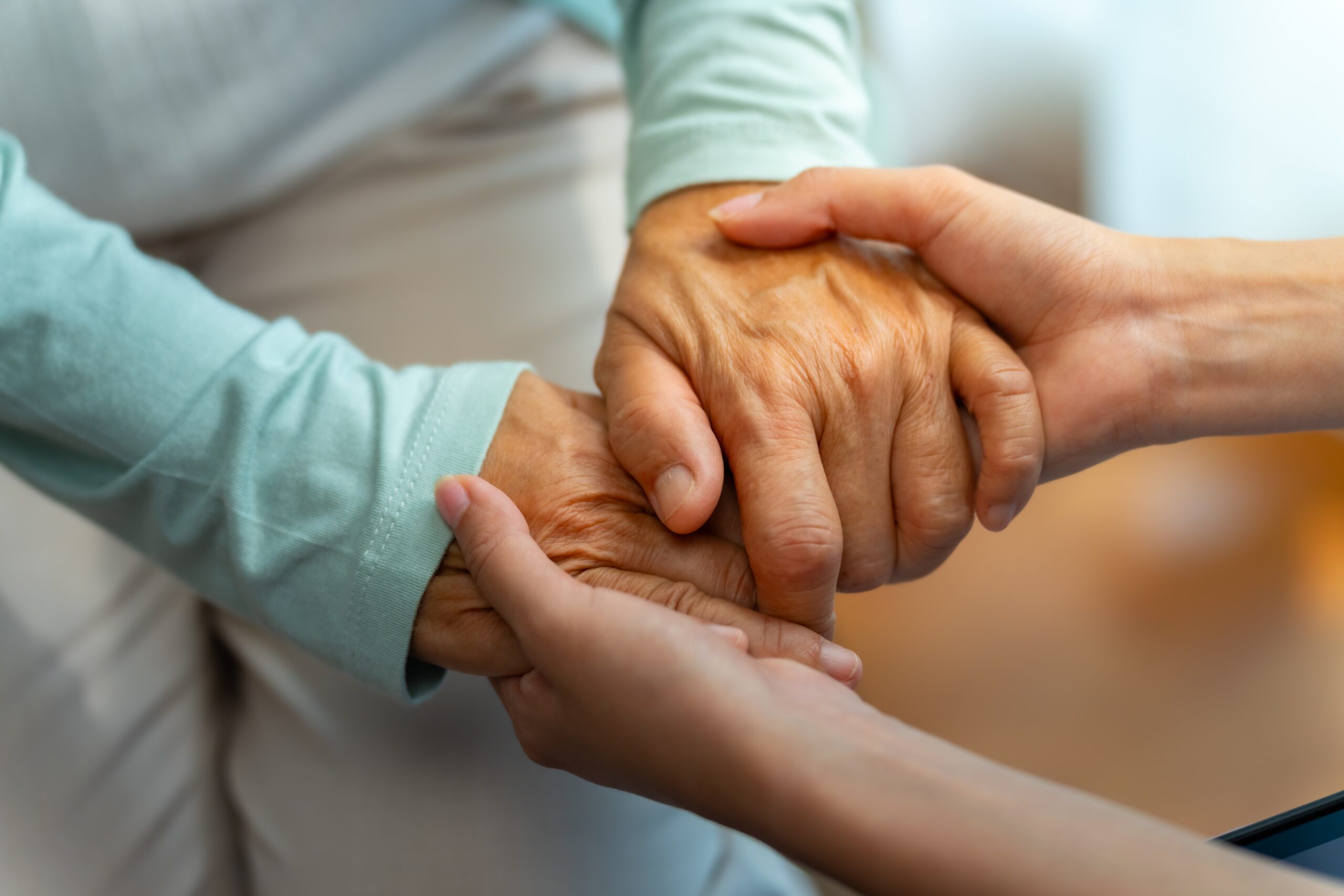 Carer gently holding an older person's hands